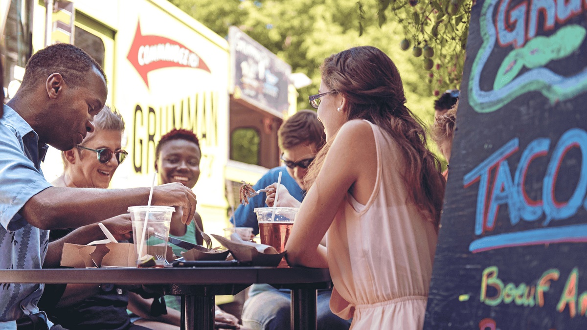 Een groepje vrienden die genieten van eten en drinken bij een foodtruck